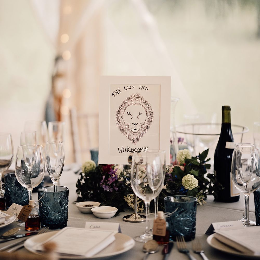 Blue coloured glassware on table for table place settings with sign showing the table named after the couple's favourite pubs 