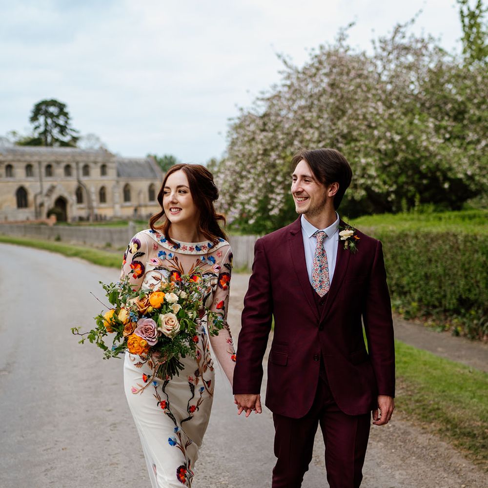 Bride and groom walk around their venue holding hands 