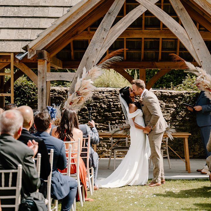 Bride and groom share their first kiss as a married couple for their outdoor wedding ceremony 