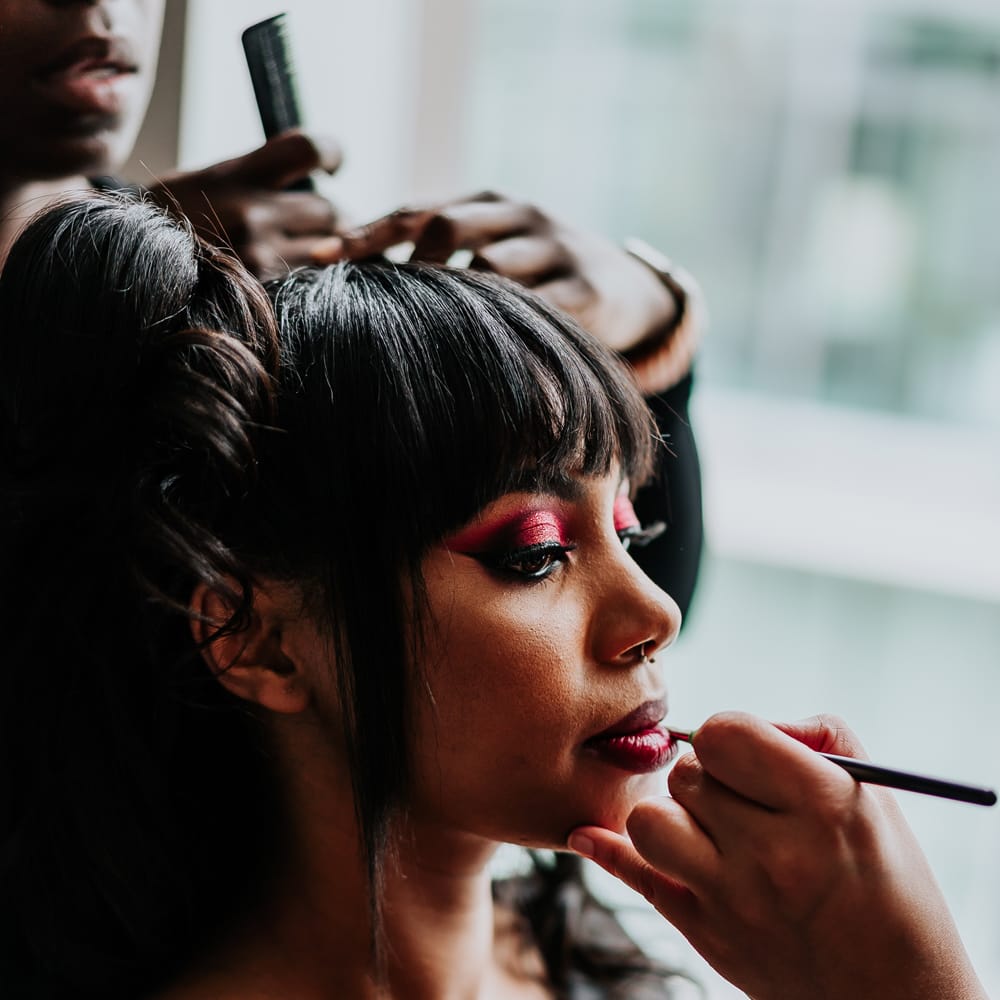 Black bride wears bold pink glitter eyeshadow and red lips on the day of her wedding 
