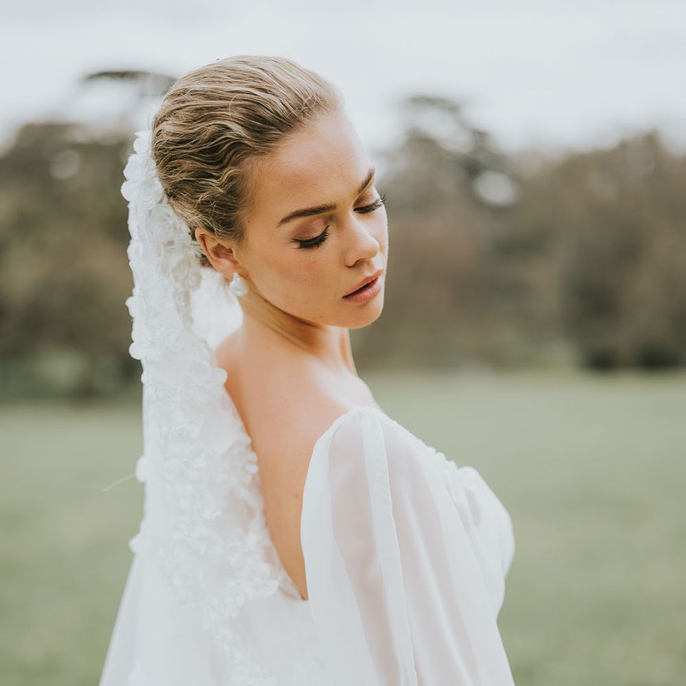 Bride with soft and natural wedding makeup with flower veil and sheer balloon sleeve wedding dress