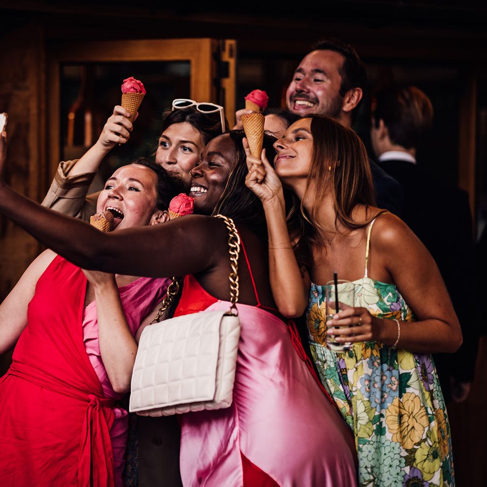 Wedding guests pose for a selfie holding up ice cream in cones 