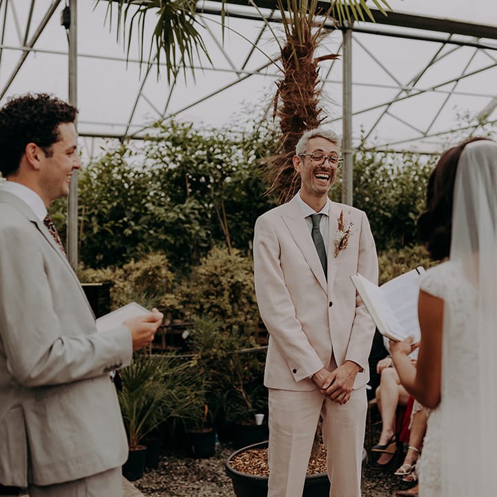 Groom laughing while the Bride reads from vow book during ceremony