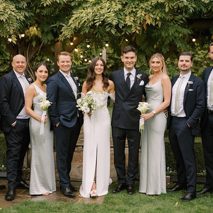 Bridesmaids in sage green satin bridesmaid dresses with the groom and the groomsmen wear sage green ties to match with white flower buttonhole