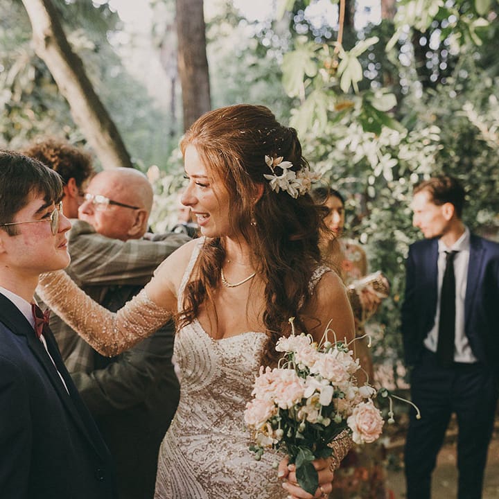 bride in a gold sparkly wedding dress with sleeves holding a pink flower bouquet 