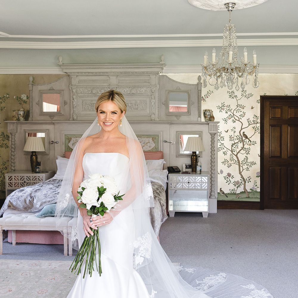 Bride in fitted mermaid wedding dress from Pronovias with pearl earrings and embroidered veil