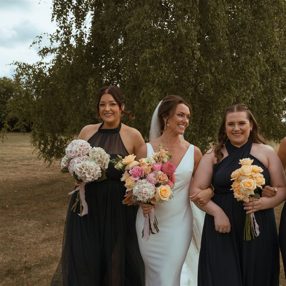 Bridesmaids in mismatched navy blue bridesmaid dresses by Rewritten Bridesmaids walking with the bride 