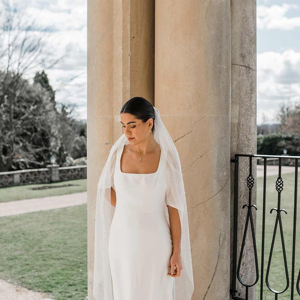 Bride in short sheer puff sleeve wedding dress with square neck and wrist loop at Buxted Park