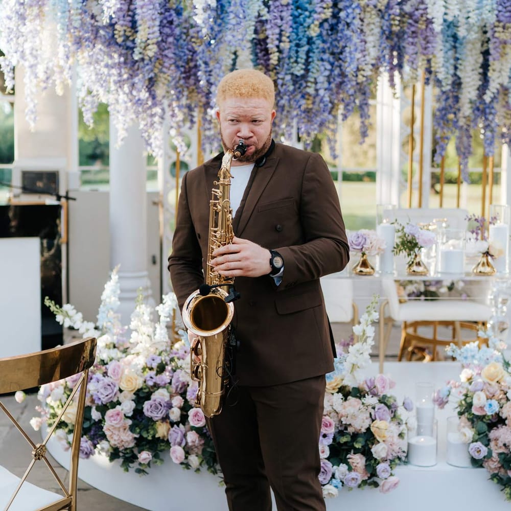 Live wedding saxophonist wearing brown suit and white trainers at Syon Park vow renewal ceremony