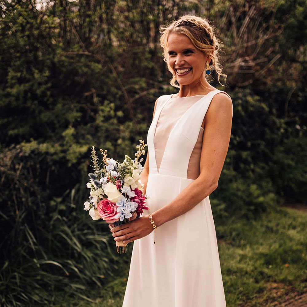 Bride in classic Andrea Hawkes Milo wedding dress with mesh insert holding colourful bouquet for spring church wedding 