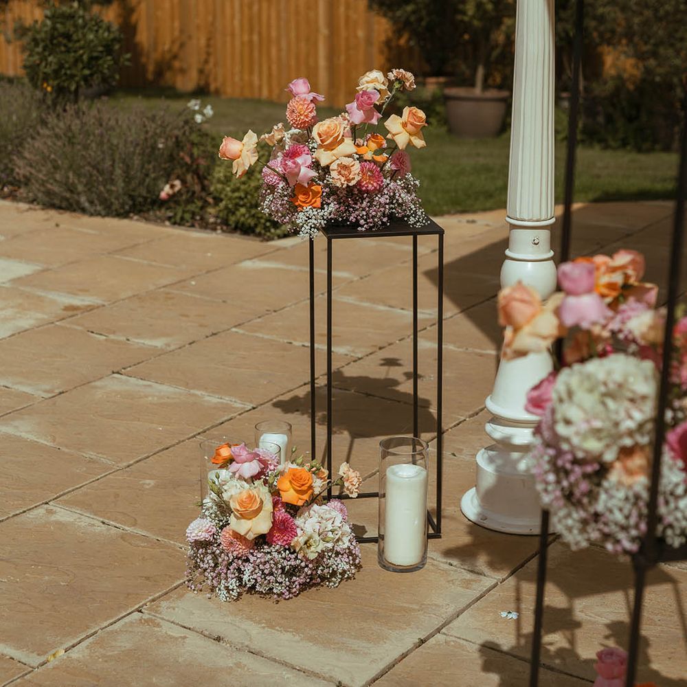 Orange and yellow wedding flower arrangements on black frames with gypsophila
