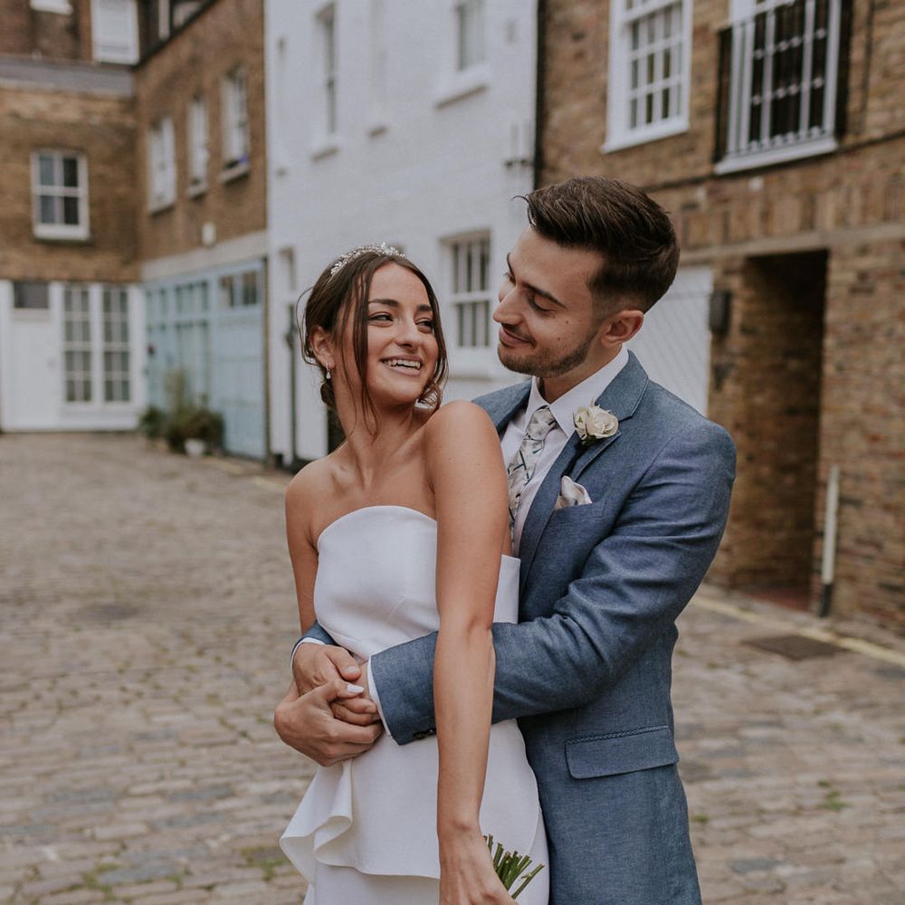 Groom in blue suit embracing his bride in Roland Mouret wedding dress