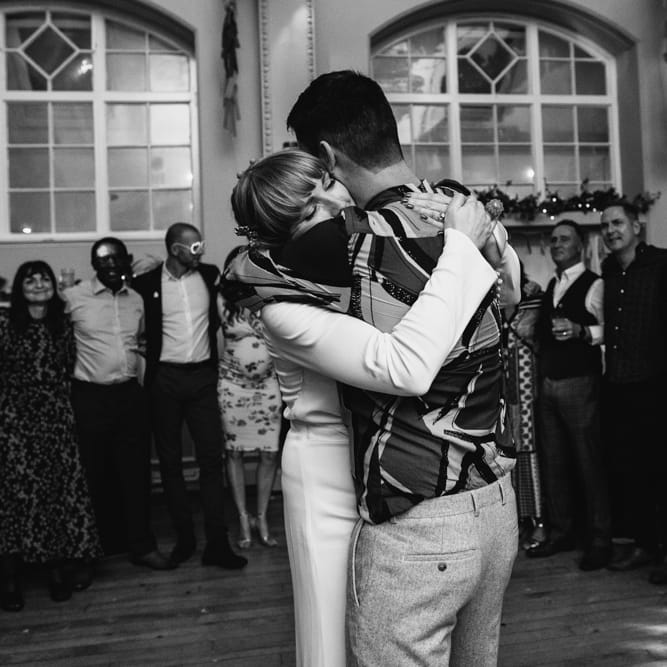 Black and white portrait of the bride and groom embracing on the dance floor 