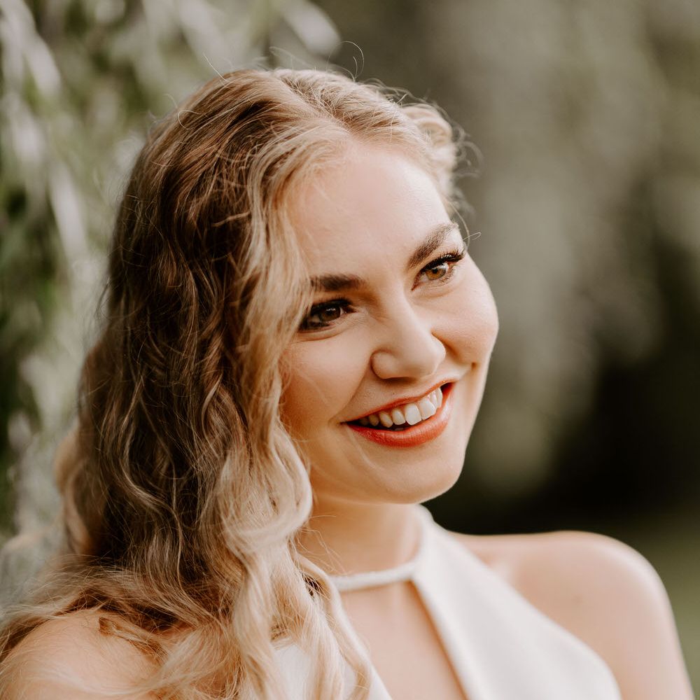Bride with long wavy relaxed wedding hair, wearing a halterneck jumpsuit for tropical theme wedding