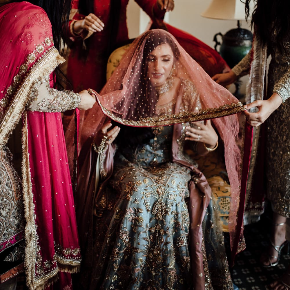 Wedding party lift veil above brides head as she gets ready