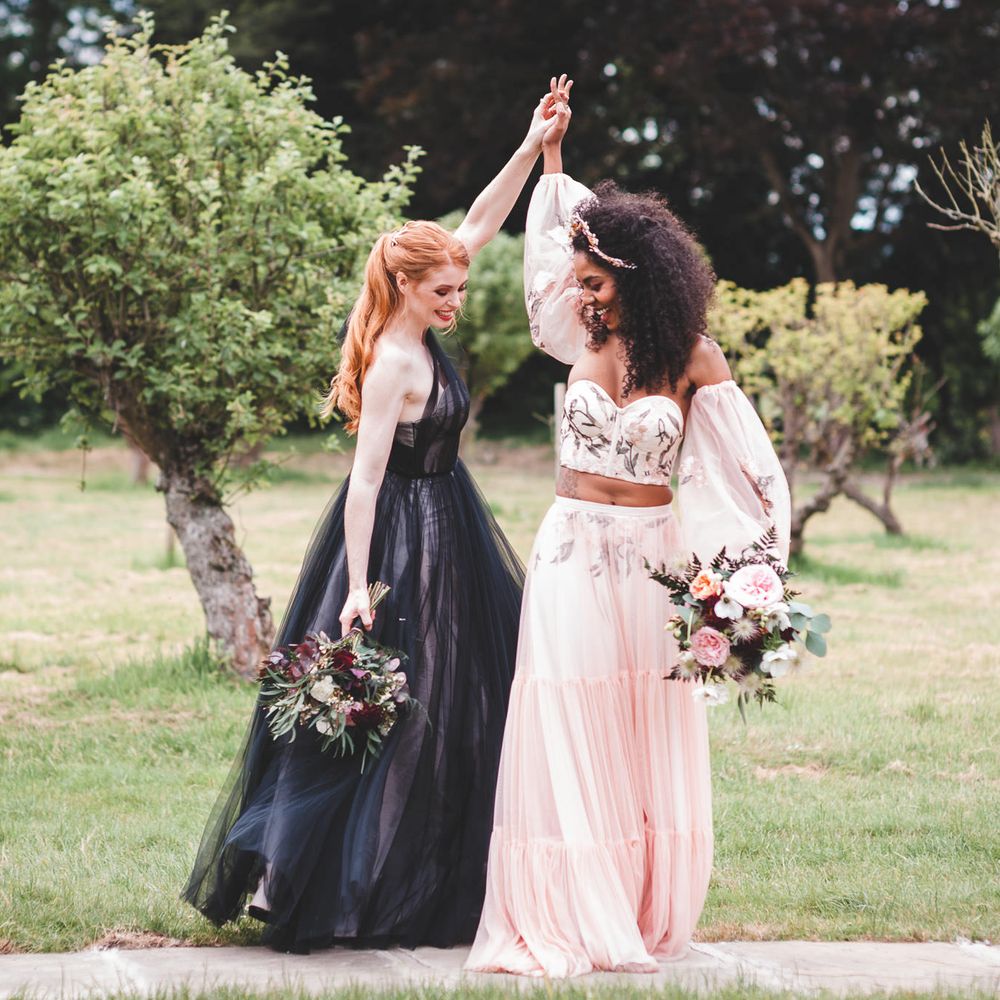 Wedding portrait of an neurodiverse couple in a black tulle wedding dress and blush pink separates dancing in a field 