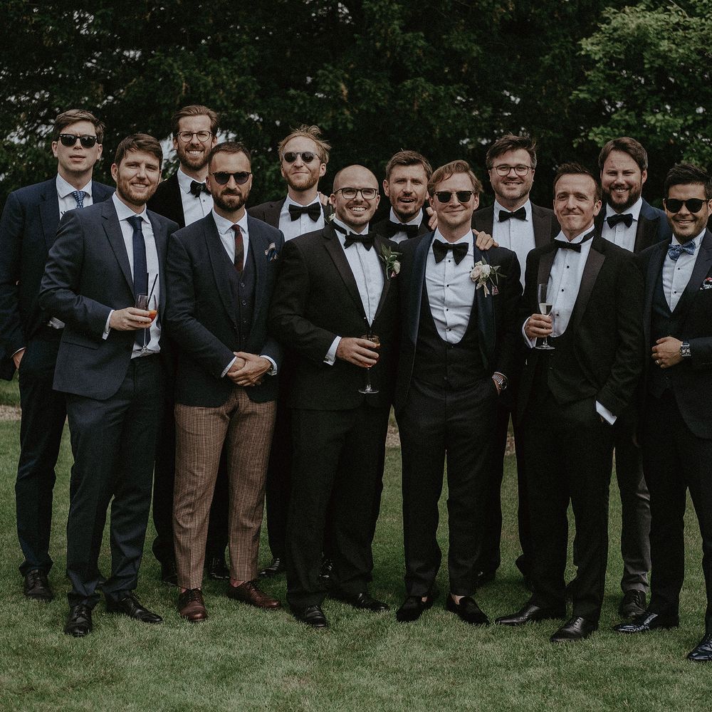 Groom stands with his groomsmen on the day of wedding in black tie