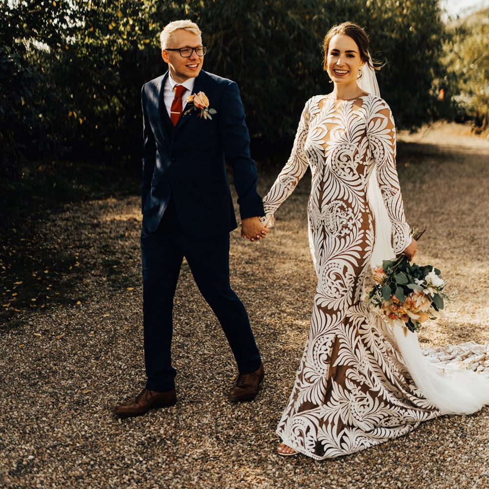 Groom with a orange autumnal accent colour tie & navy suit holds Boho bride in her Rue De Seine 