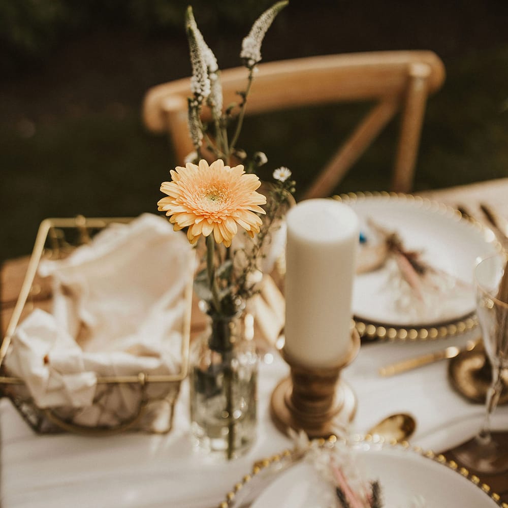 Rustic tablescape complete with gold cutlery and yellow flower