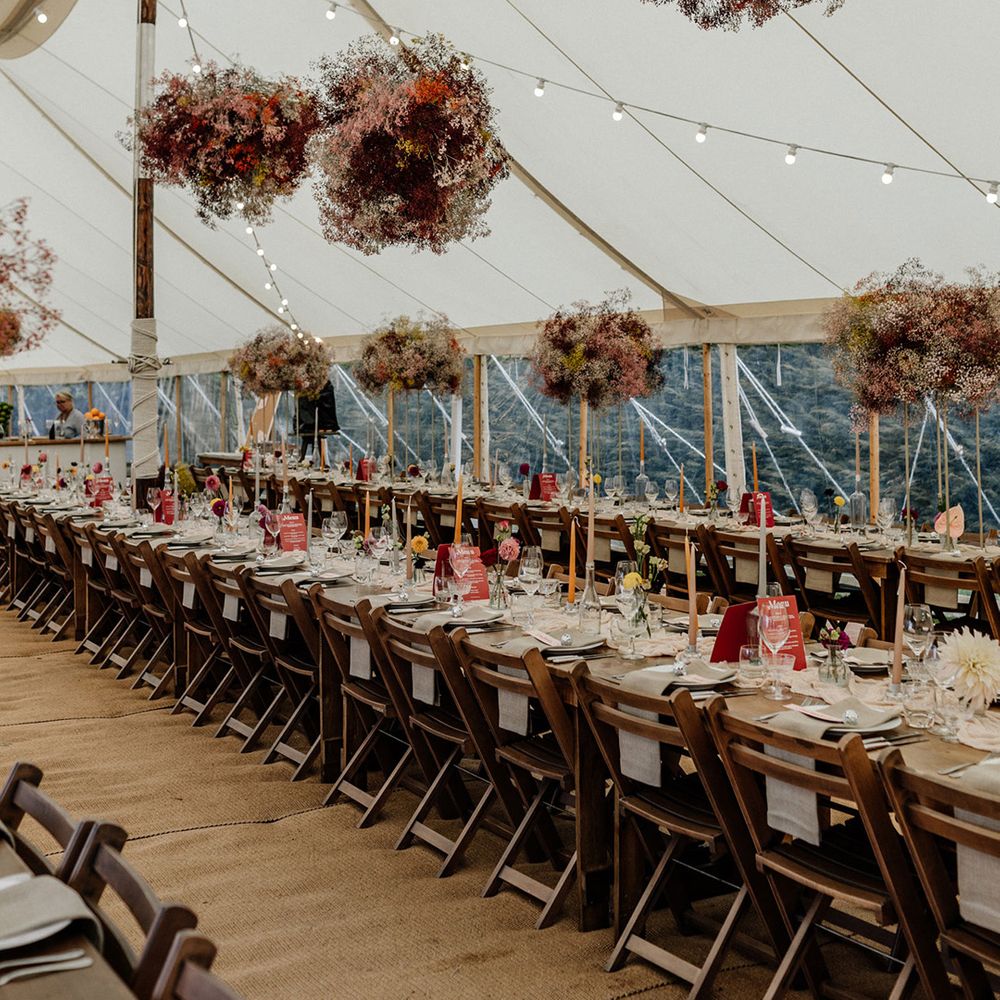 Stylish marquee wedding reception decor with gypsophila flower clouds, festoon lights and taper candles 