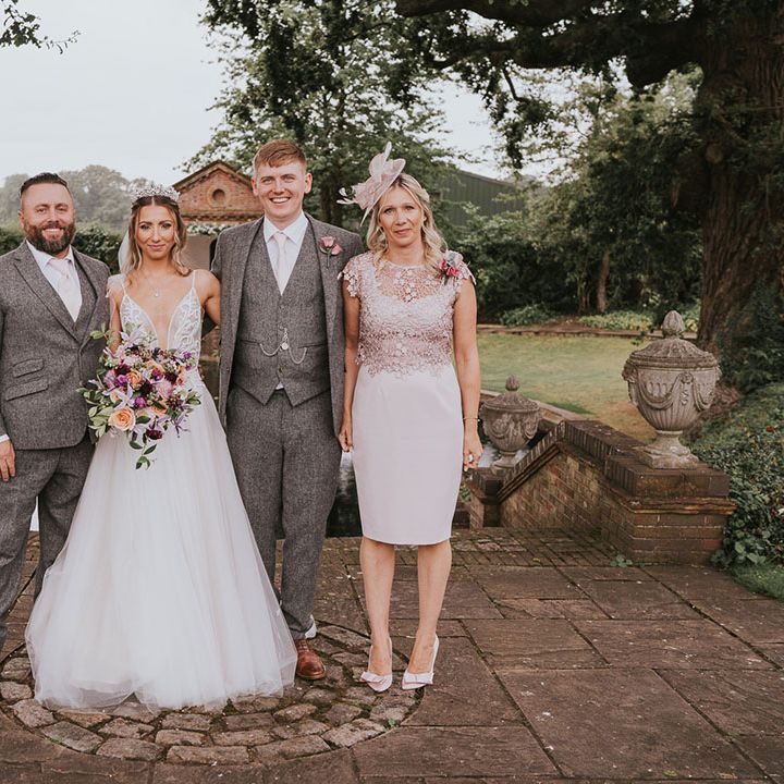 Bride and groom stand with parents on their wedding day at Micklefield Hall