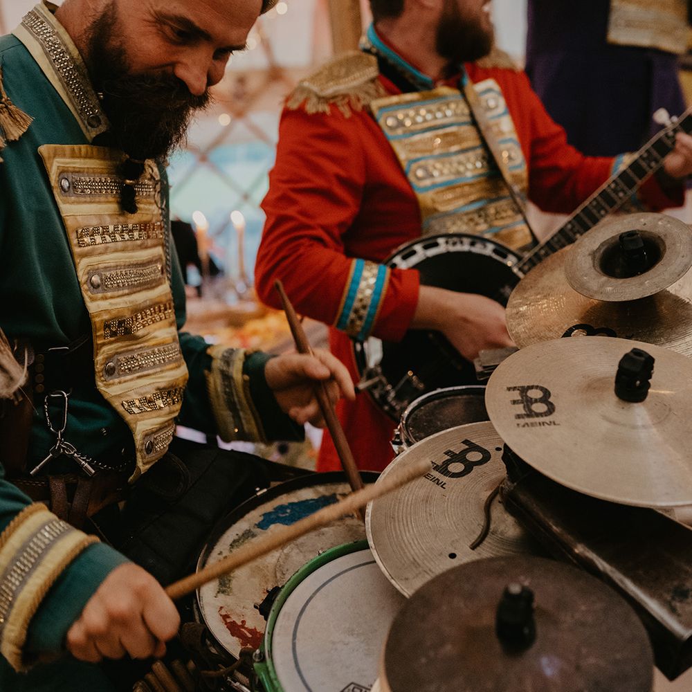 Wedding band entertainment with man in green outfit and gold turban plays the drums 