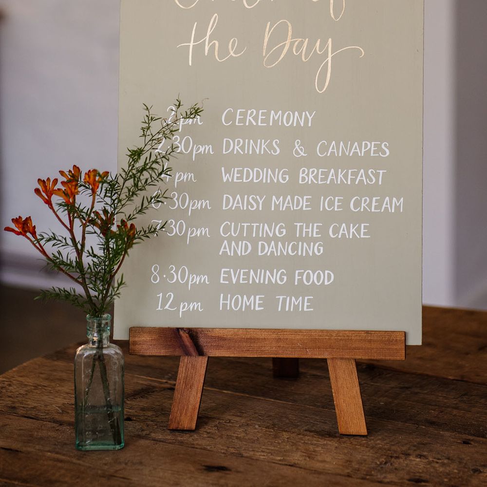 Order of the day sign with white font and small flowers 