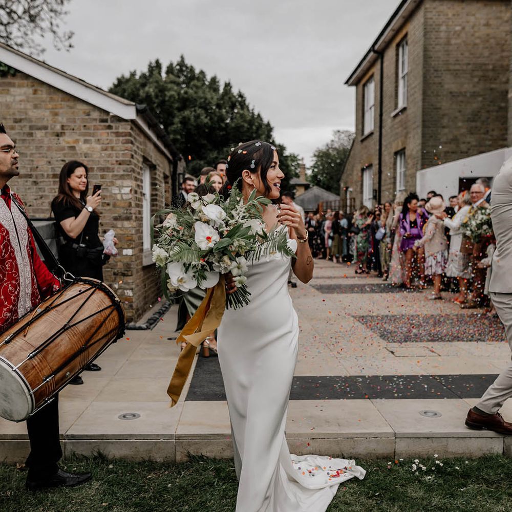 Stunning bride in a satin slip Sabina Motasem wedding dress holding a white flower and foliage wedding bouquet 