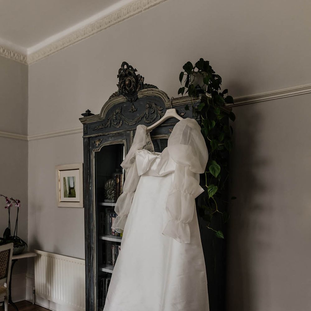 Jesus Peiro wedding dress with long sheer sleeves hanging up on the wedding morning 