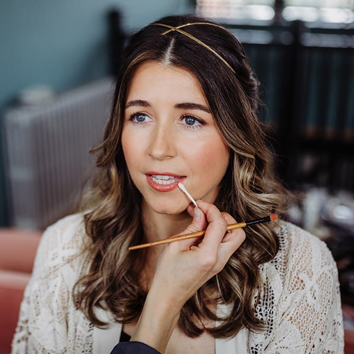 Bride wearing a gold hair piece gets her makeup done for her wedding day