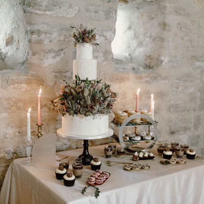 wedding cake table with three tier wedding cake decorated with dried and fresh flowers 