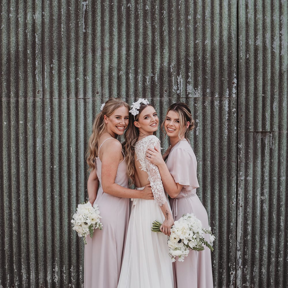 Bride stand with bridesmaids in pale pink Rewritten bridesmaid dresses
