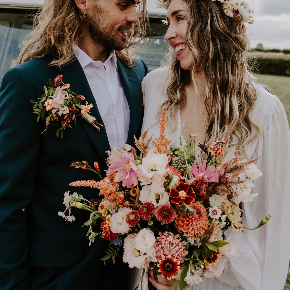 Bride holds colourful bouquet as groom wears matching floral buttonhole 