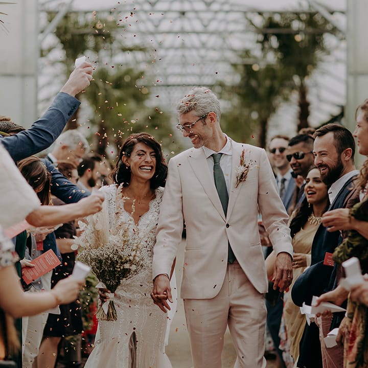 Bride and Groom walk down aisle together after ceremony with confetti