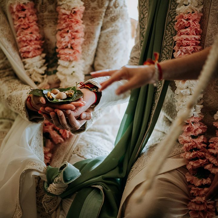 Grooms with matching lei's and sherwani's during multicultural wedding ceremony in barn 