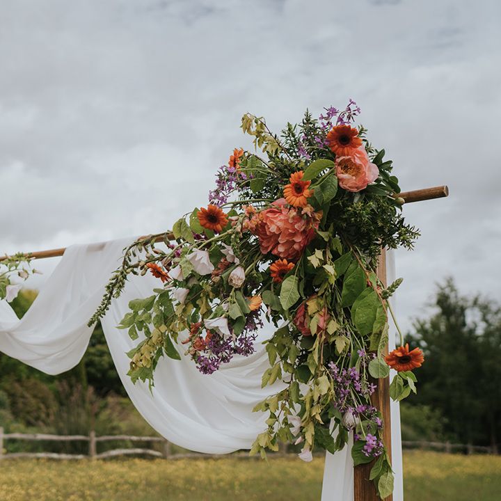 Wooden arch complete with white drapes and colourful floral decor