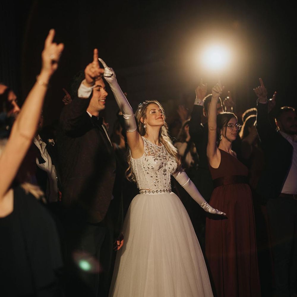 Bride in sparkly tulle princess skirt Jenny Packham wedding dress with satin glover ad silver headband enjoying the music 