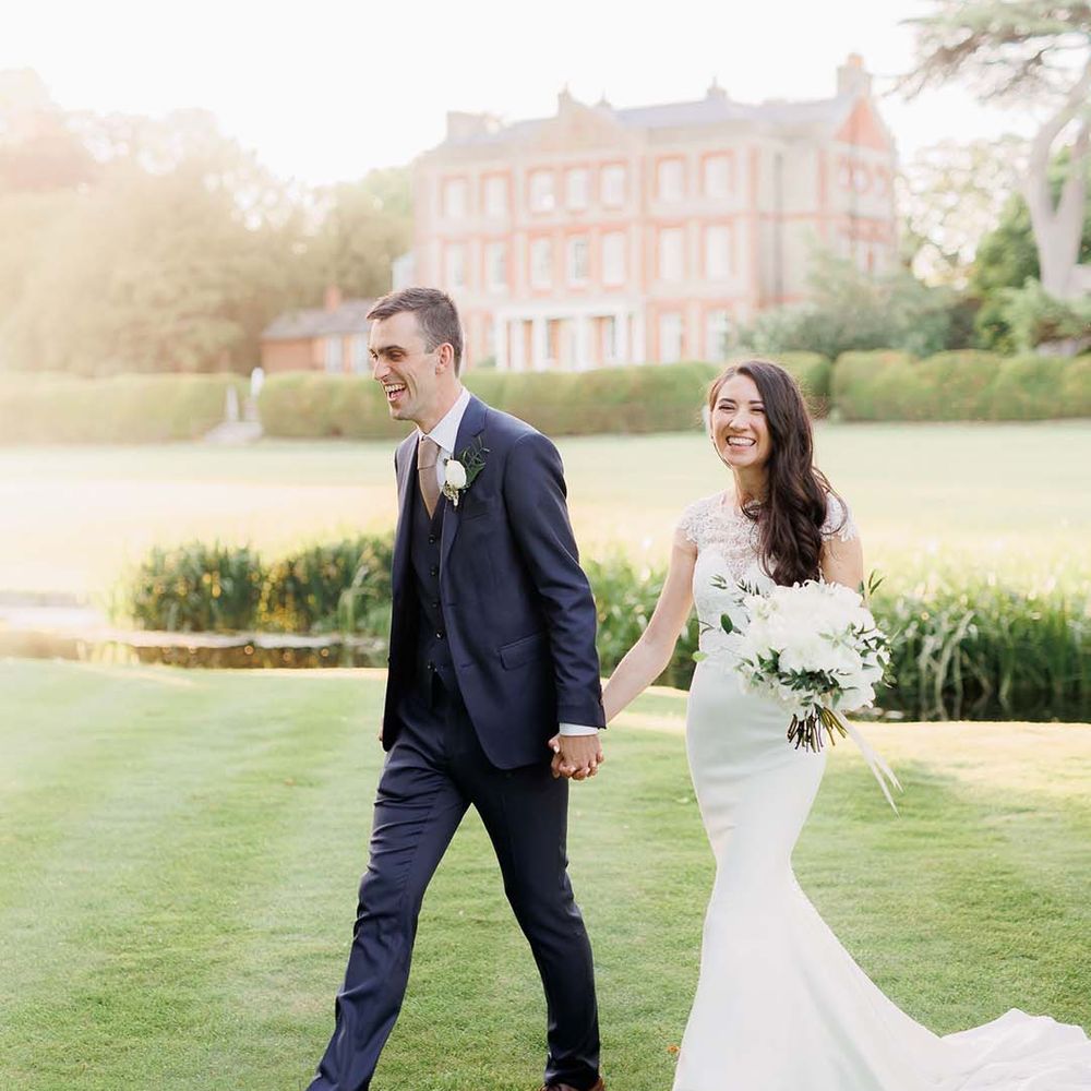Bride in a fitted Kelly Faetanini wedding dress with lace detail and groom in a navy suit at Ardington House wedding 