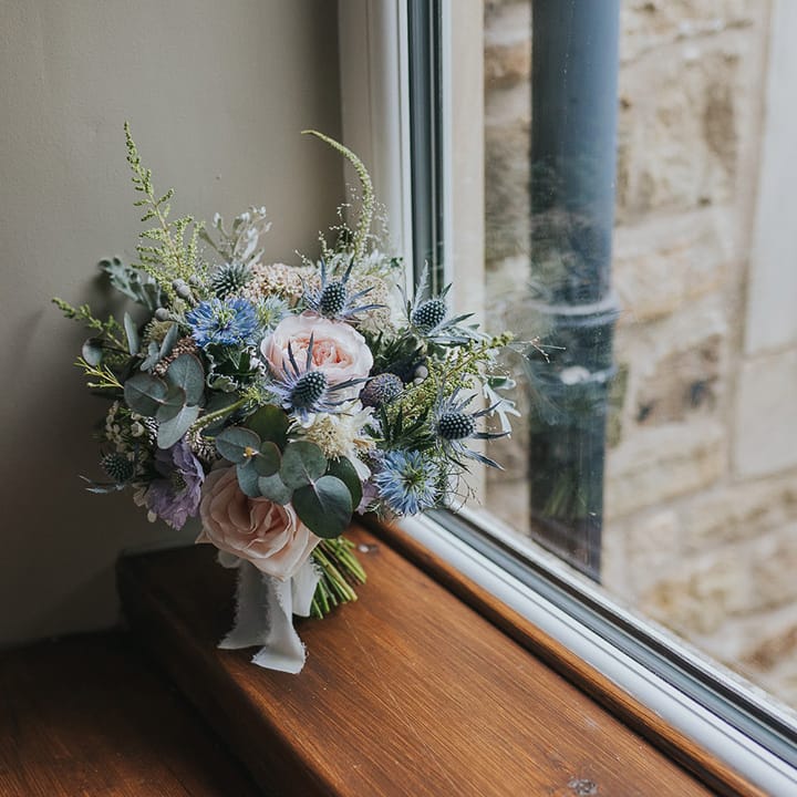 pastel pink and blue wedding bouquet with thistles and roses