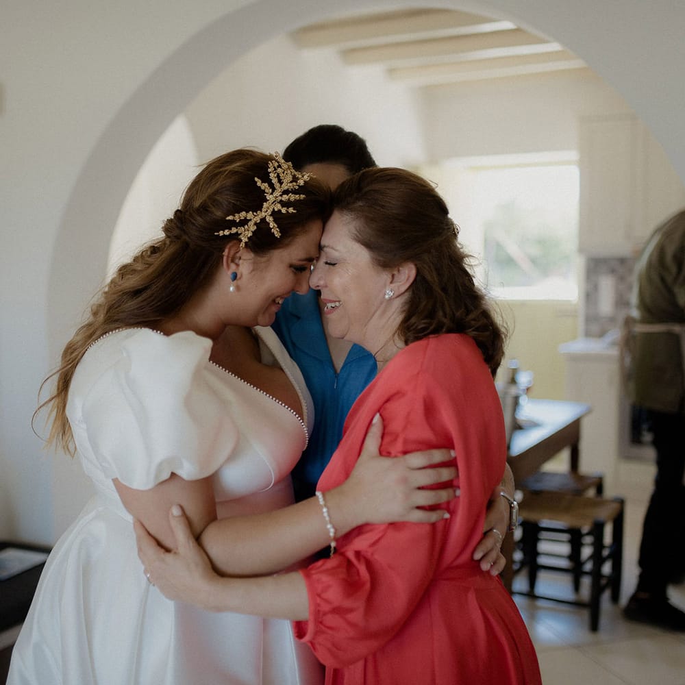 Bride in satin dress and bridal crown embracing family before wedding ceremony 