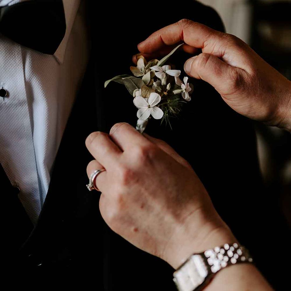 groom in a tuxedo and bow tie with a white buttonhole flower 