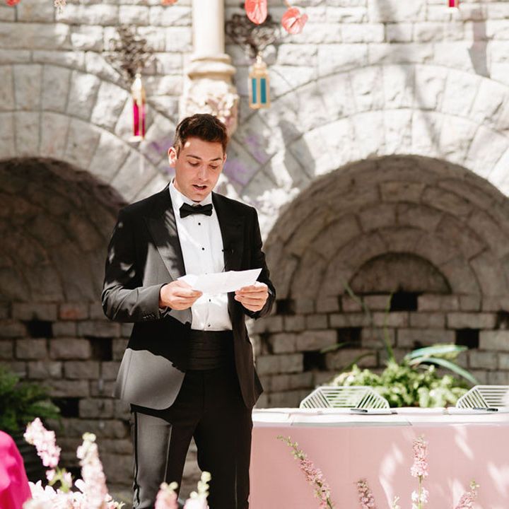 Wedding guest in black tie reads out a wedding reading during the ceremony in the Orangery at De Vere Tortworth Court