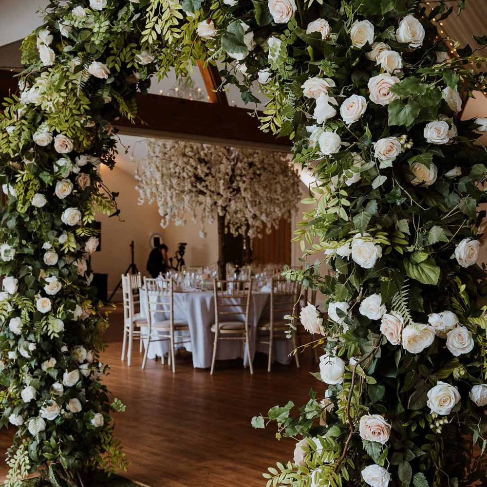 White garden rose and foliage wedding floral arch in reception room at Tredudwell Manor 