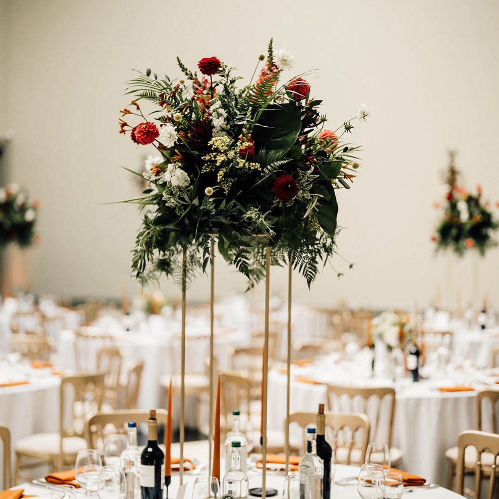 Tall floral wedding table centrepiece with orange flowers for contemporary twist at classic country house wedding 