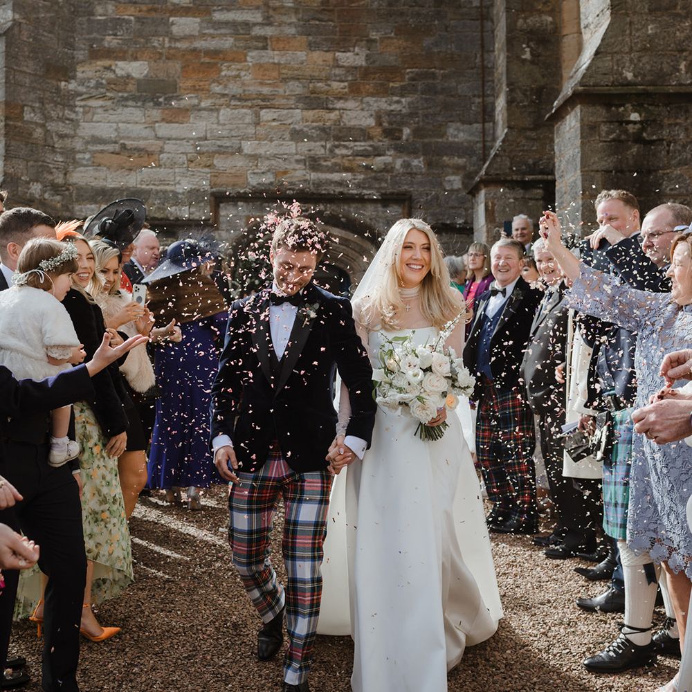 The bride and groom walk out to confetti after their wedding 