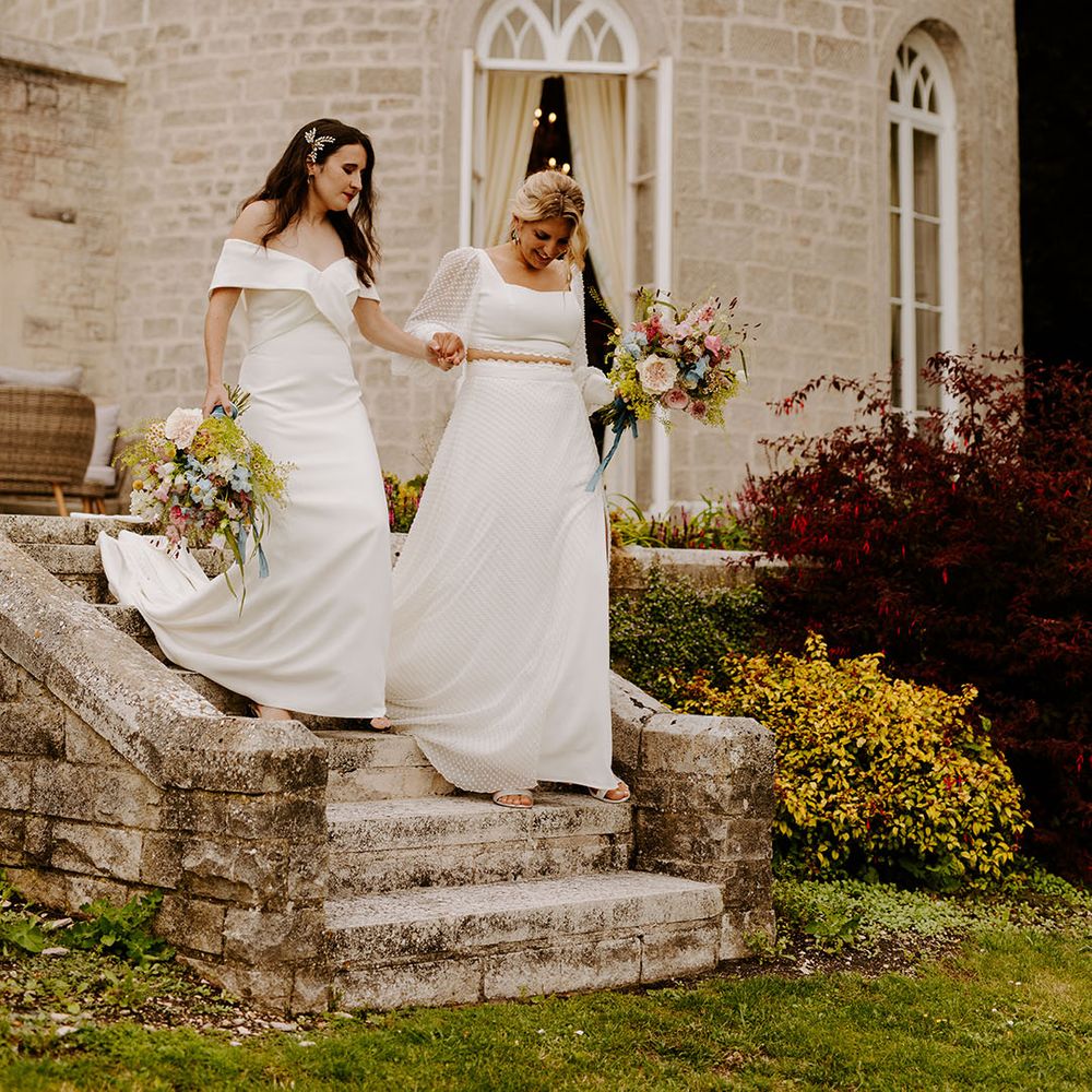 Castle wedding venue in Dorset with one bride in an off the shoulder wedding dress and another bride in a long sleeve two piece bridal set 