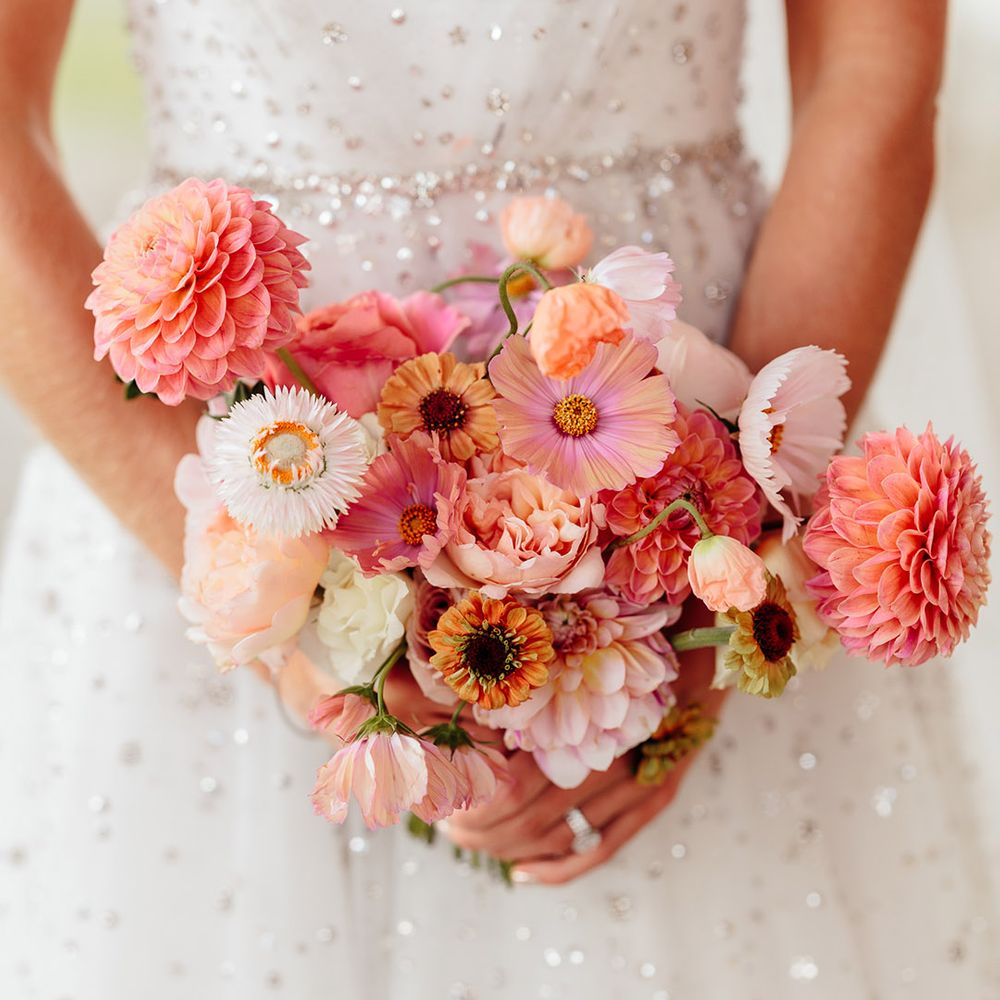 Bride holding pink and white wedding bouquet with sweet pea, dahlias, and cosmos 