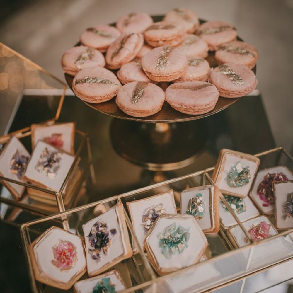 Pink macarons and shortbread biscuits decorated with icing that looks like a crystal with gold dusting 