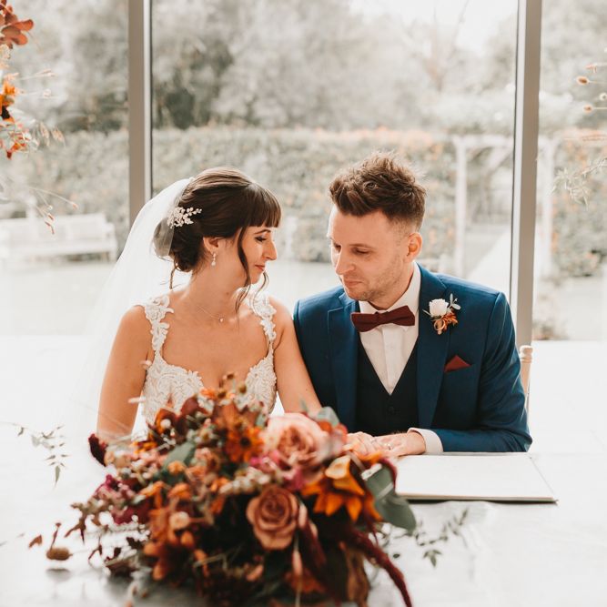 Bride and groom signing the register with autumn flowers