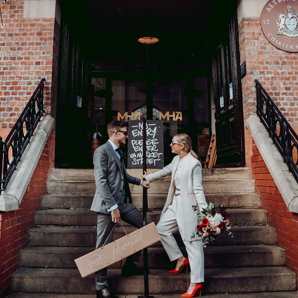 Bride in Massimo Dutti jumpsuit with red shoes and groom in grey check suit by Joanne Lawrence Photography